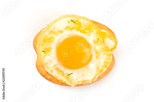 A photo of a quail egg, fried sunny side up, shot from above on a cracker on a white background with a place for text