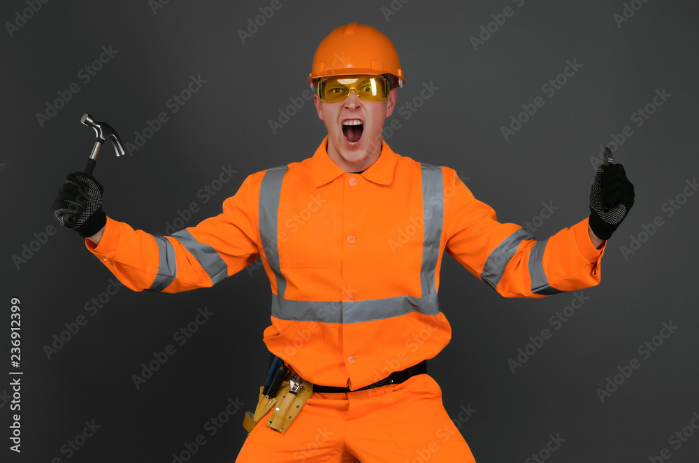 Angry and annoyed builder worker or foreman with hammer and with a pliers is shouting. A foreman discontented by a work. Angry and annoyed builder worker or foreman with hammer and with a pliers is shouting. A foreman discontented by a work.