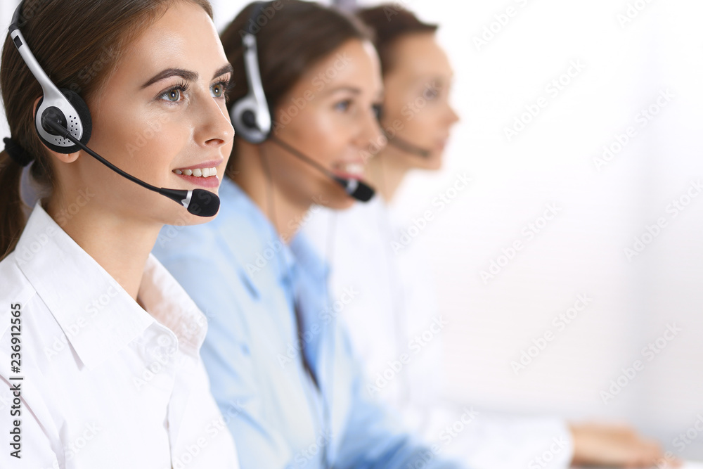Call center. Group of operators at work. Focus at beautiful business woman in headset Call center. Group of operators at work. Focus at beautiful business woman in headset