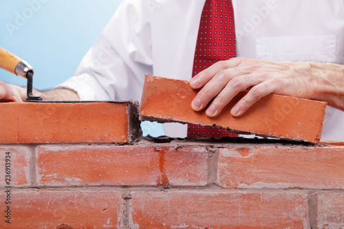 Businessman building a brick wall.