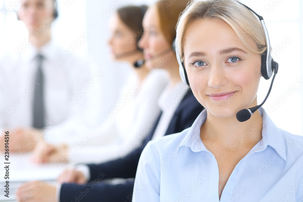 Call center. Group of operators at work. Focus at blonde business woman in headset Call center. Group of operators at work. Focus at blonde business woman in headset