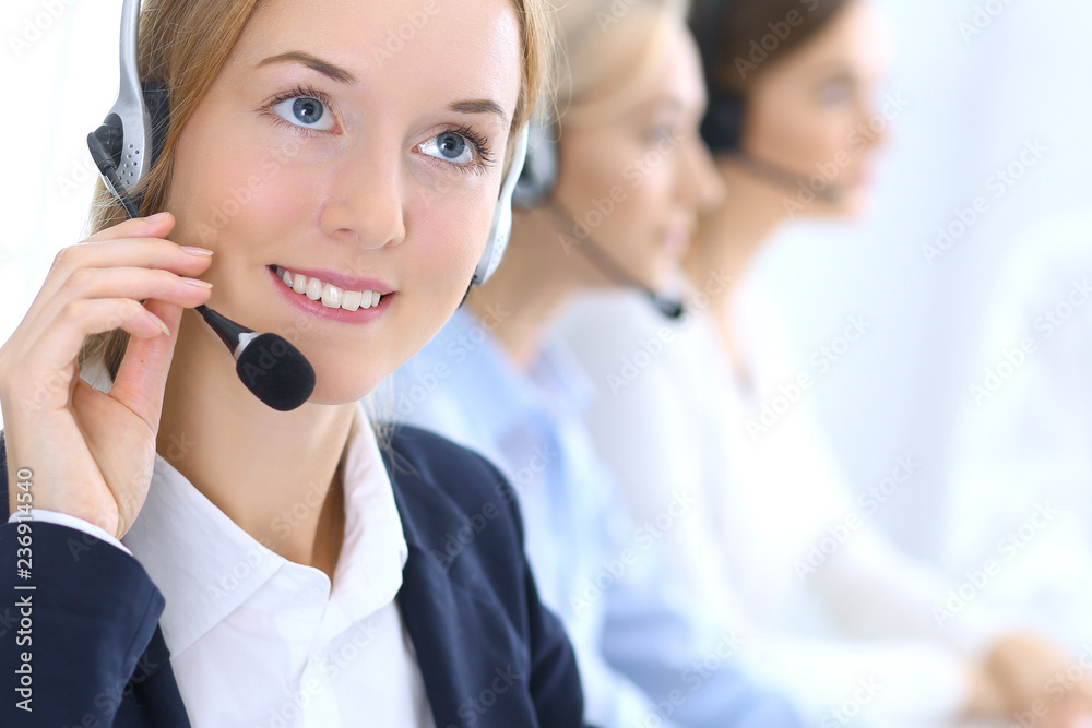 Call center. Group of operators at work. Focus at brunette business woman in headset