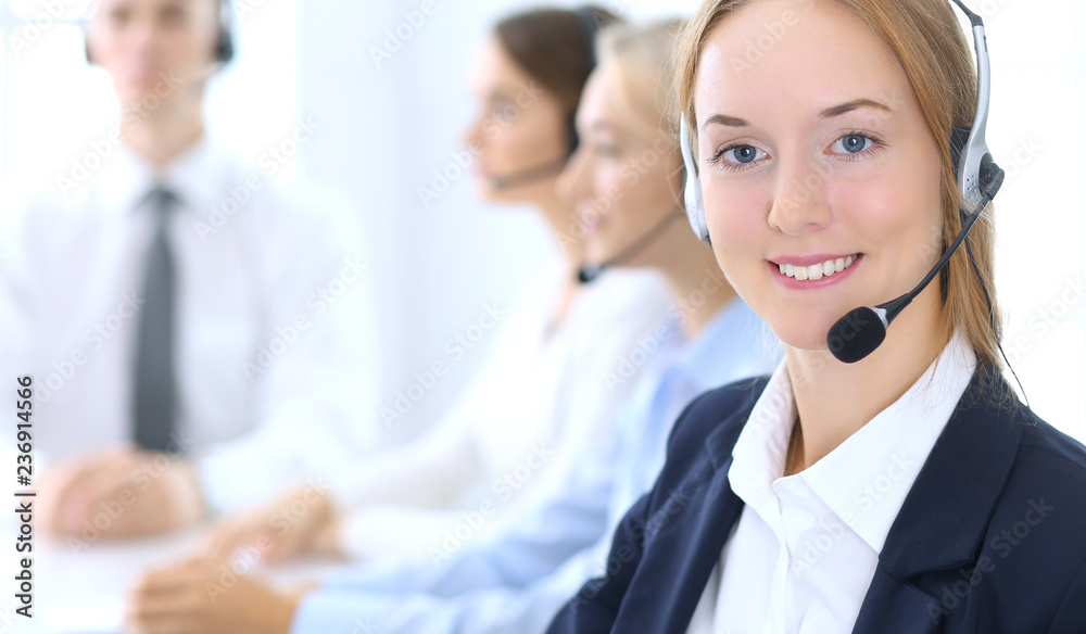 Call center. Group of operators at work. Focus at brunette business woman in headset