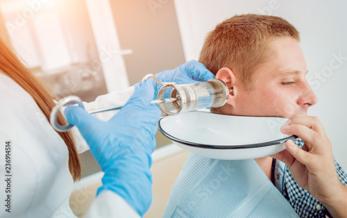 Medical ear washing with water in big syringe