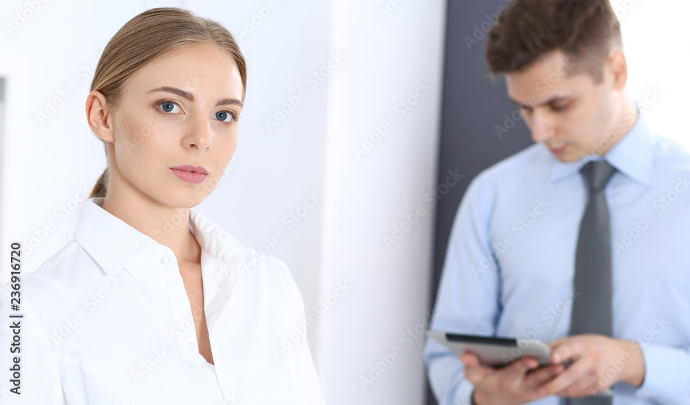 Beautiful blonde businesswoman using tablet pc while standing straight in a brightly lit office. Business concept Beautiful blonde businesswoman using tablet pc while standing straight in a brightly lit office. Business concept