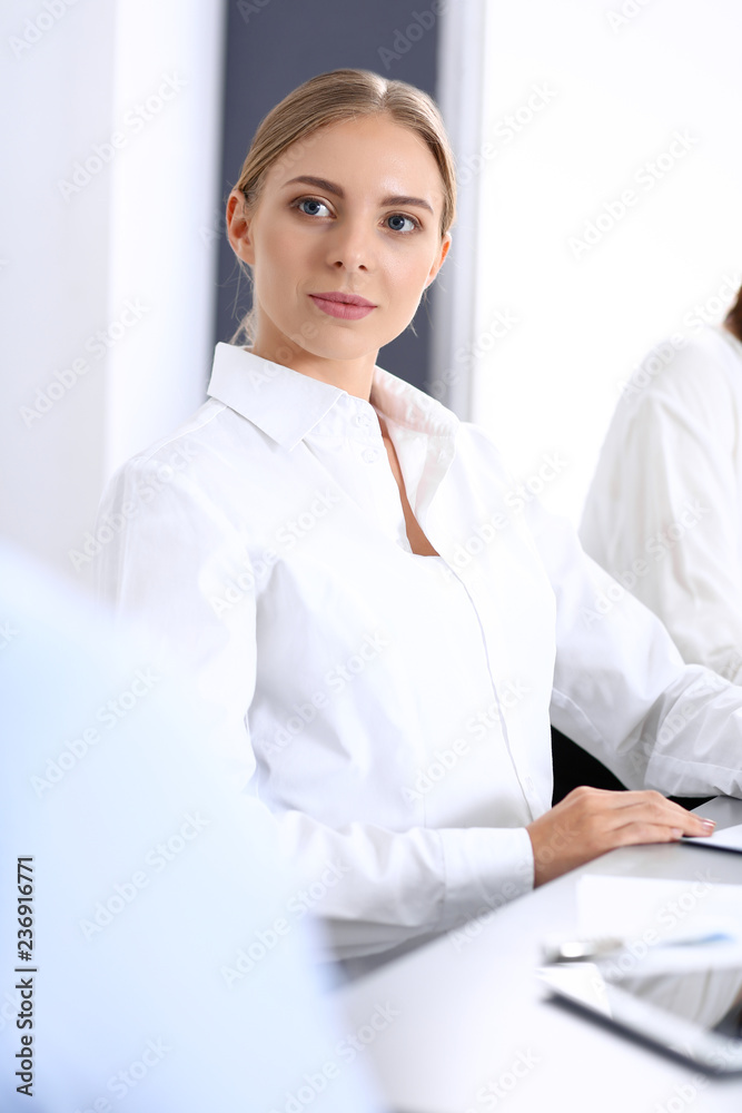 Group of business people or lawyers discussing terms of transaction in office. Colleagues working all together. Focus at blonde woman. Meeting and teamwork concept Group of business people or lawyers discussing terms of transaction in office. Colleagues working all together. Focus at blonde woman. Meeting and teamwork concept