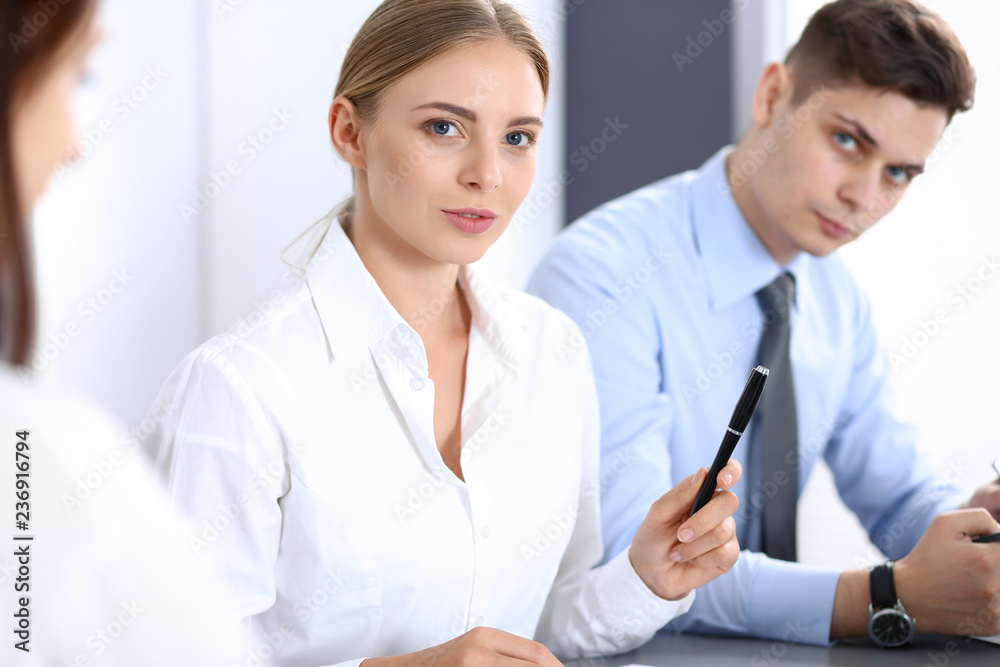 Group of business people or lawyers discussing terms of transaction in office. Colleagues working all together. Focus at blonde woman. Meeting and teamwork concept Group of business people or lawyers discussing terms of transaction in office. Colleagues working all together. Focus at blonde woman. Meeting and teamwork concept