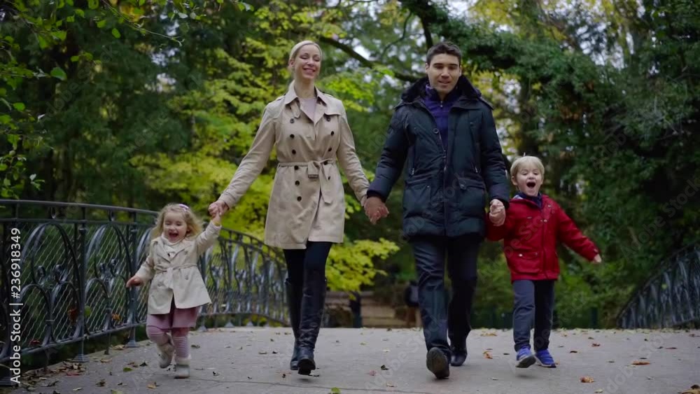 happy caucasian family is running together in park, parents is holding hands of little kids happy caucasian family is running together in park, parents is holding hands of little kids