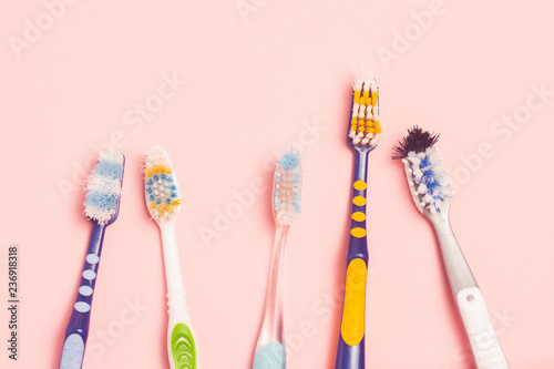 Several different used toothbrushes on a pink background. Toothbrush change concept  oral hygiene  big and friendly family  toothbrush selection. Flat lay  top view