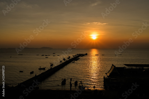 Sunset at the bridge by the sea with a boat surrounded.