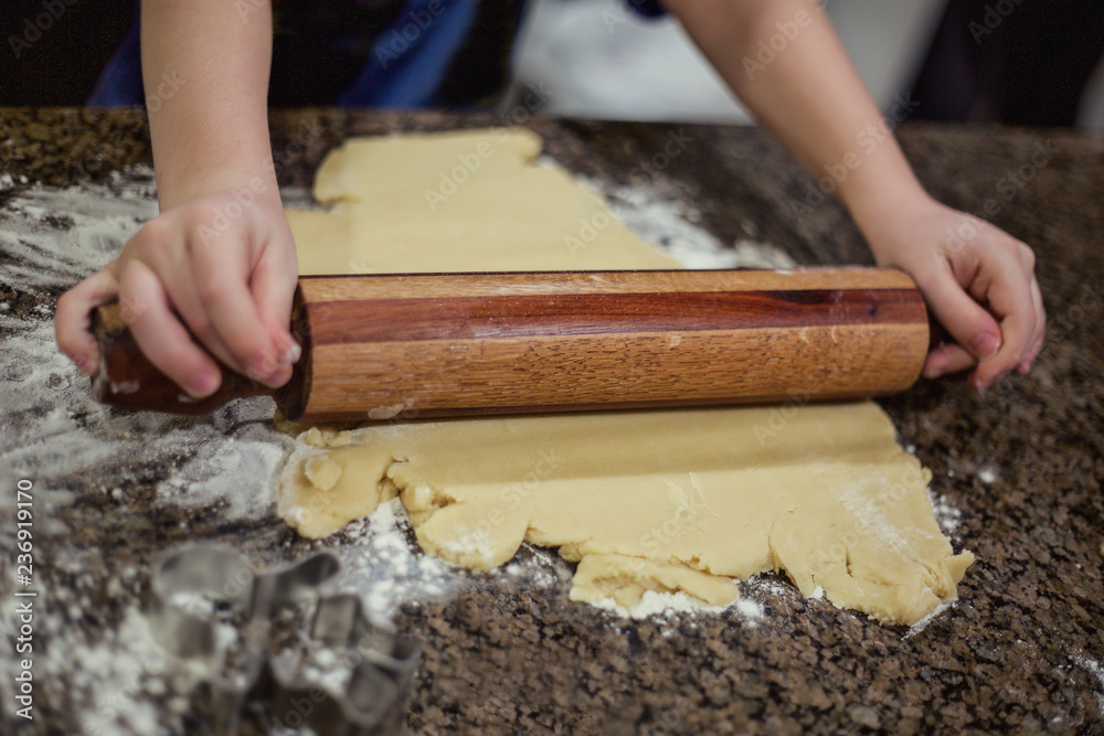 Preparing Christmas cookie dough using a rolling pin to prepare the dough. Selective focus on rolling the sugar cookie dough on the marble countertop Preparing Christmas cookie dough using a rolling pin to prepare the dough. Selective focus on rolling the sugar cookie dough on the marble countertop