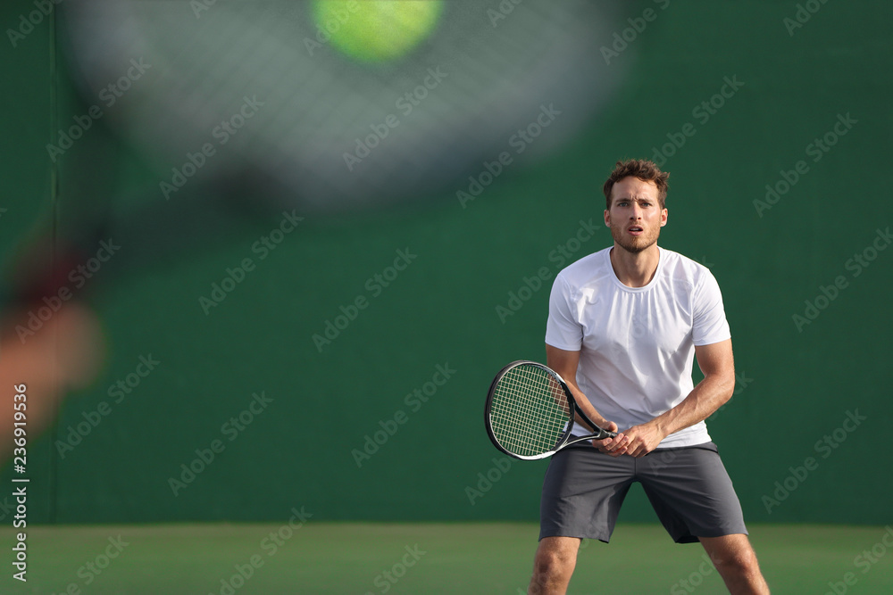 Tennis player focused on other player hitting ball with racket on court. Men  sport athletes players playing tennis match together. Two professional  tennis players on hard outdoor court during game. Stock Photo