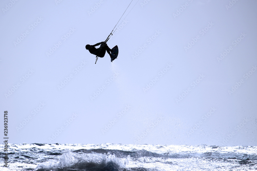Kite-surfer with spray of water behind in the air