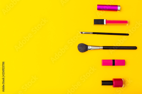 Lip gloss and makeup brush on yellow background. Bright colors