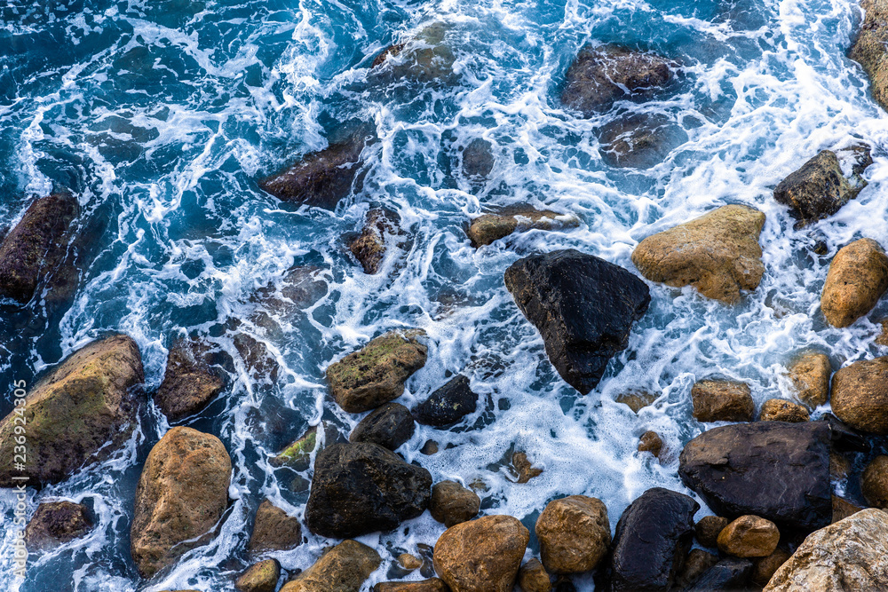 Moving wave and blue water of mediterranean sea touching rock beach making some small white bubble on surface. Moving wave and blue water of mediterranean sea touching rock beach making some small white bubble on surface.