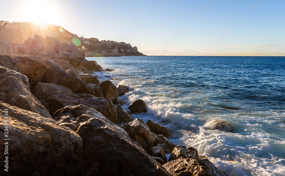 Moving wave and water of mediterranean sea touching rock beach making some splashing water in the air at sunrise. Moving wave and water of mediterranean sea touching rock beach making some splashing water in the air at sunrise.
