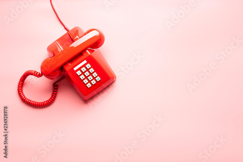 vintage red telephone on pink desk