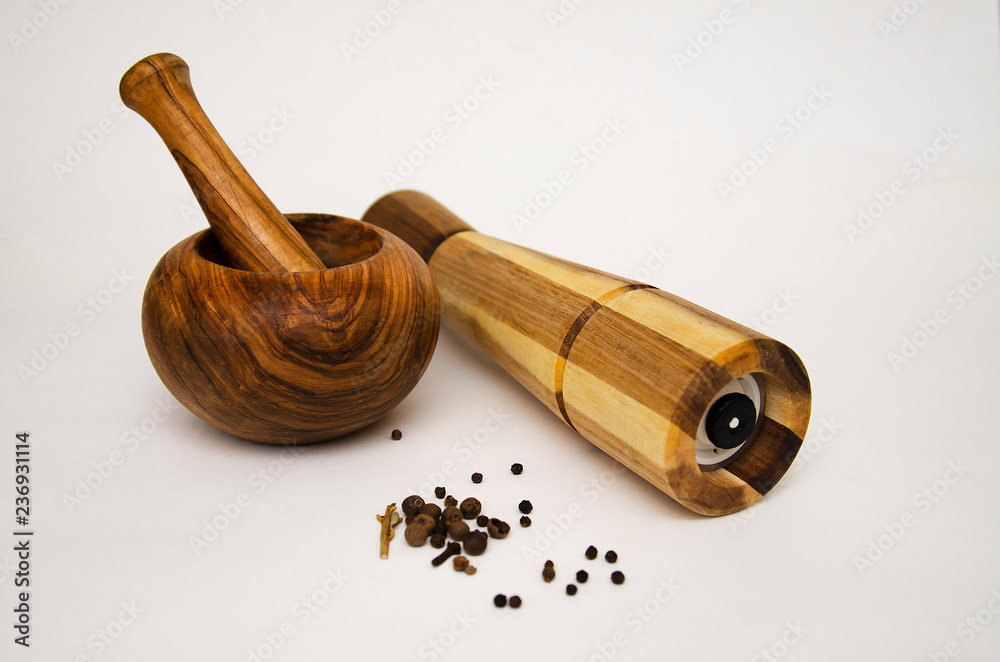 wooden mortar and mill for grinding different spices on light background