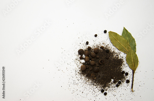 ground black pepper, peas, allspice and Bay leaf on white background