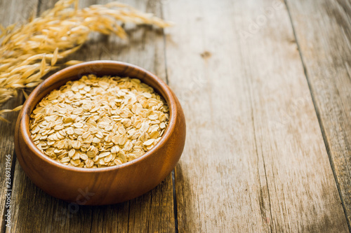 Wooden bowl with uncooked oats on the rustic wooden background. Selective focus. Shallow depth of field.