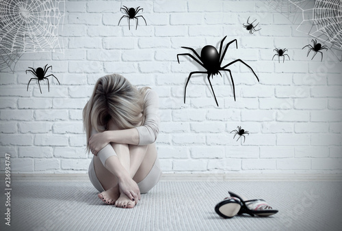 Woman sitting on the floor and looking on imaginary spider. photo