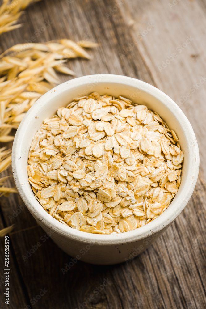 Bowl with uncooked oats on the rustic wooden background. Selective focus. Shallow depth of field. Bowl with uncooked oats on the rustic wooden background. Selective focus. Shallow depth of field.