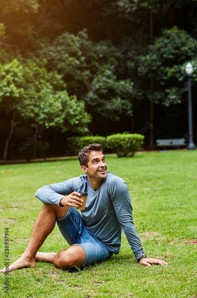 Guy relaxing in park with a coffee, smiling Guy relaxing in park with a coffee, smiling