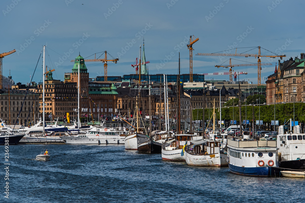 Stockholm harbor view, moored ships, yachts and boats along city embankment and urban architecture on background