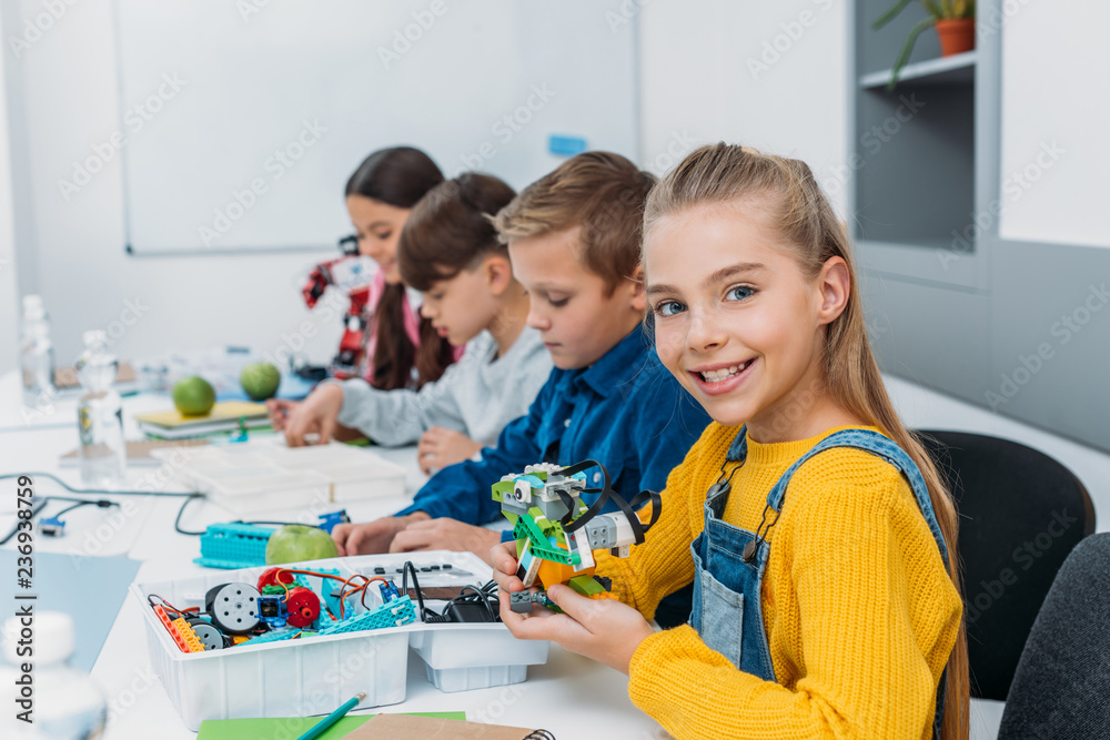 cheerful classmates making a robot during STEM robotics class cheerful classmates making a robot during STEM robotics class