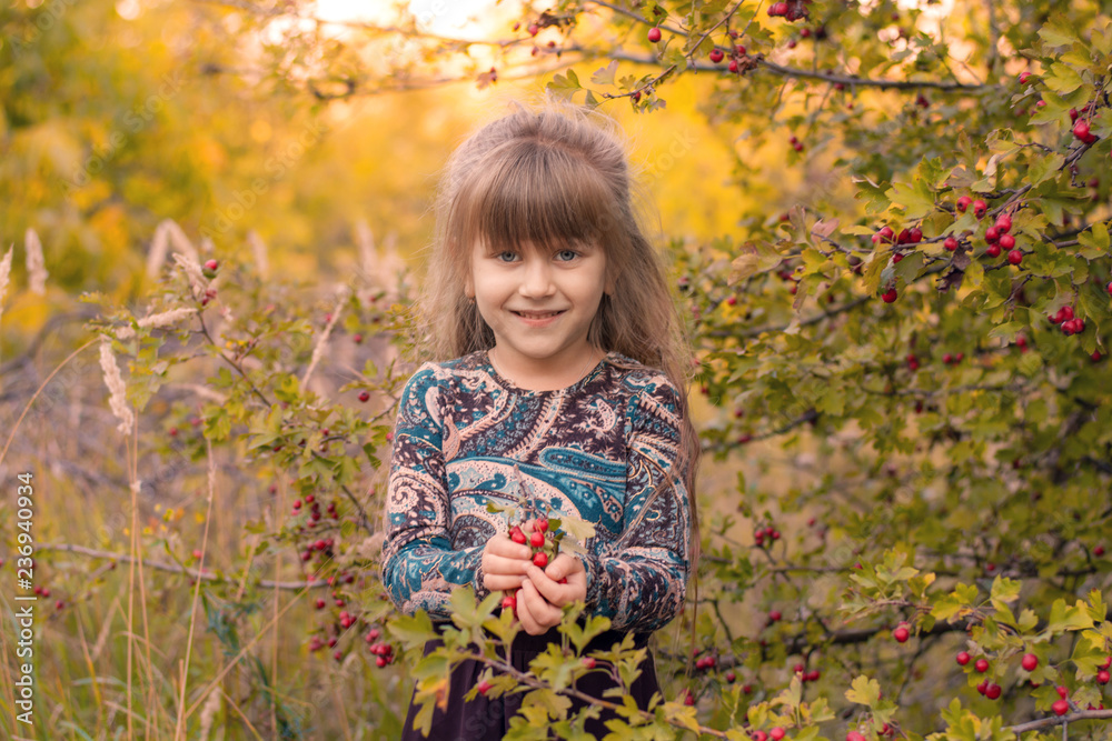 Beautiful girl with long hair at sunset in the forest. Portrait of a girl. Baby with berries in hand at sunset Beautiful girl with long hair at sunset in the forest. Portrait of a girl. Baby with berries in hand at sunset