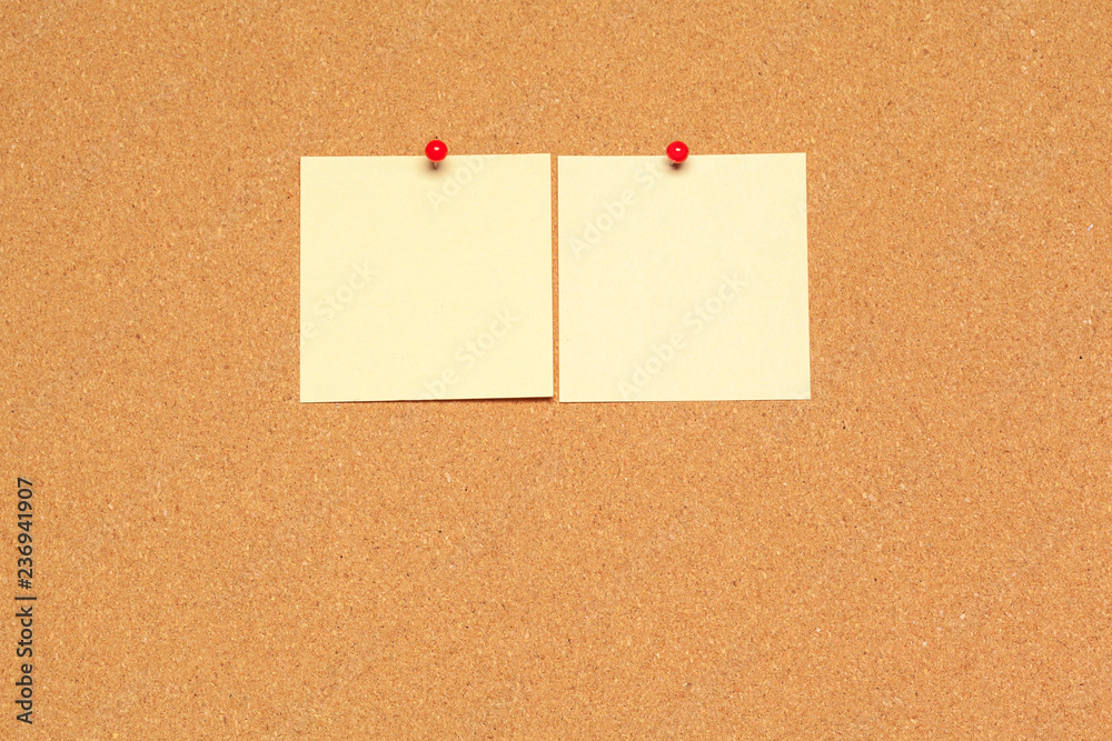 Sticky note pinned on cork board with thumbtacks Sticky note pinned on cork board with thumbtacks
