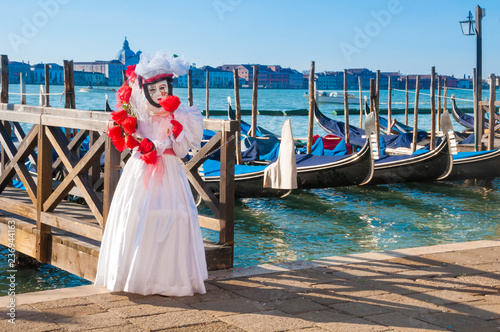 Person wearing venitian carnival mask in front of gondolas in Grand Canal during Venice carnival in Italy © Maresol