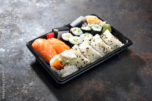 Sushi lunch. Hosomaki, futomaki i nigiri zestaw sushi. Tacka z kawałkami sushi , imbirem , wasabi i sosem sojowym na ciemnym tle.