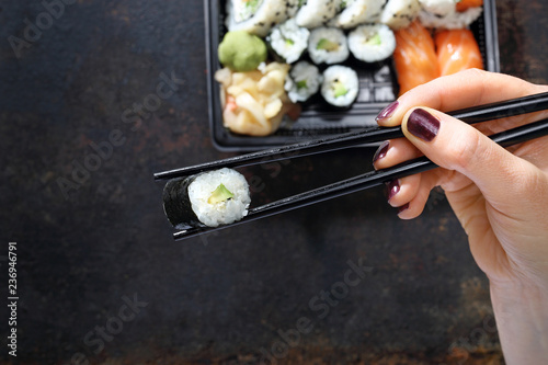 Tacka z kawałkami sushi , imbirem , wasabi i sosem sojowym na ciemnym tle.