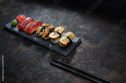 Nigiri na kamiennym talerzu. Apetyczne, różnorodne sushi na kamiennym talerzu. Kompozycja na ciemnym tle.