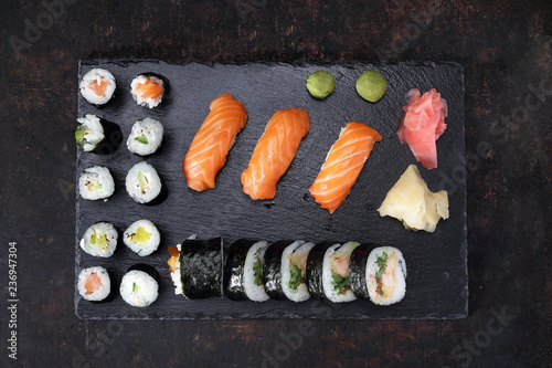 Sushi menu. Apetyczne, różnorodne sushi na kamiennym talerzu. Kompozycja na ciemnym tle.