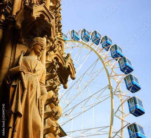 Christmas Ferris wheel in front of the cathedral of Metz . Architectural detail - statue of woman with covered eyes. Metz, France. Abstract concepts. 