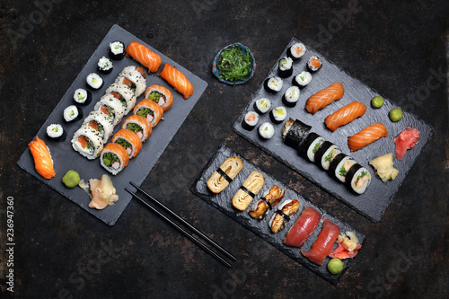 Kuchnia japońska, sushi. Apetyczne, różnorodne sushi na kamiennym talerzu. Kompozycja na ciemnym tle.