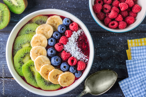 Healthy breakfast with delicious acai smoothie in bowl on dark background