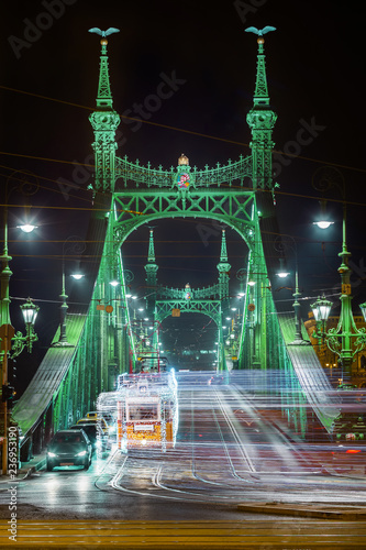 Budapest, Hungary - Festively decorated light tram (fenyvillamos) on the move at Liberty Bridge (Szabadsag hid) by night. Christmas season in Budapest photo