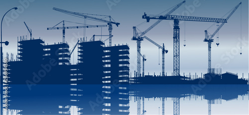 nine cranes above blue buildings with reflection