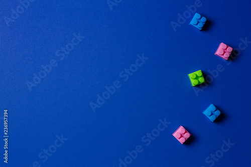 Baby kid toys background. Colorful plastic construction blocks on blue background © vejaa