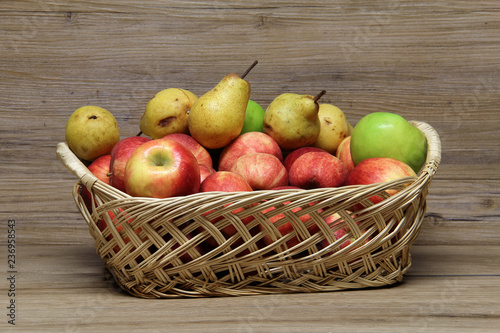 Basket with ripe apples and pears on the table stands