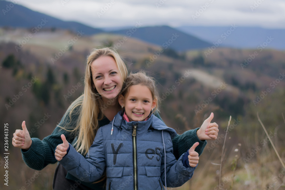 Moms and daughter are smiling and happy against the backdrop of the mountains. Mountains and people. Blond woman with her daughter