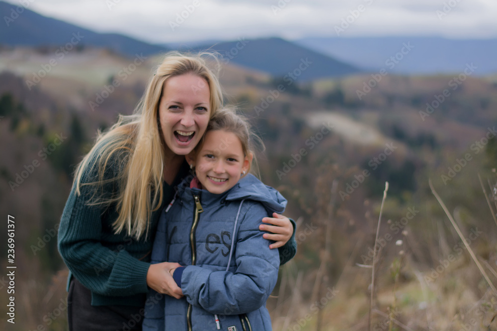 Moms and daughter are smiling and happy against the backdrop of the mountains. Mountains and people. Blond woman with her daughter.  mothers Day