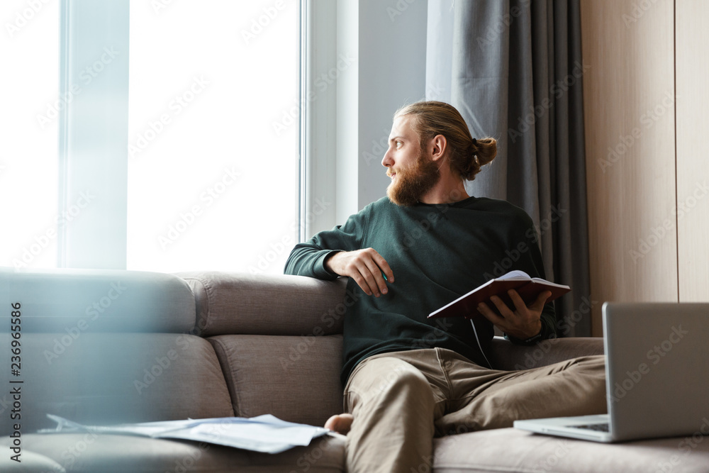 Concentrated young bearded man sitting in home