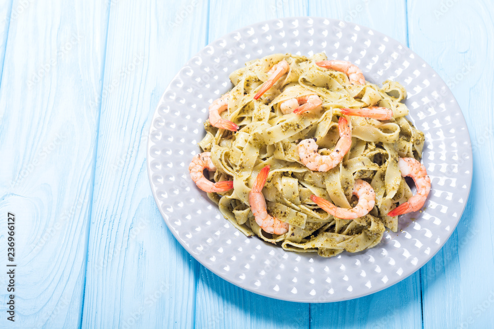 Pasta tagliatelle with sauce pesto and shrimps . Italian food background