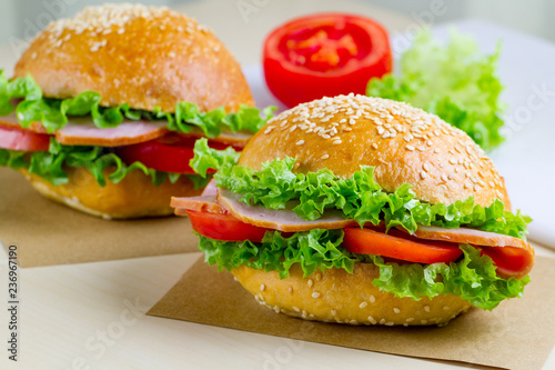 Appetizing sesame buns with fresh lettuce, tomato and ham for snack. Homemade sandwiches