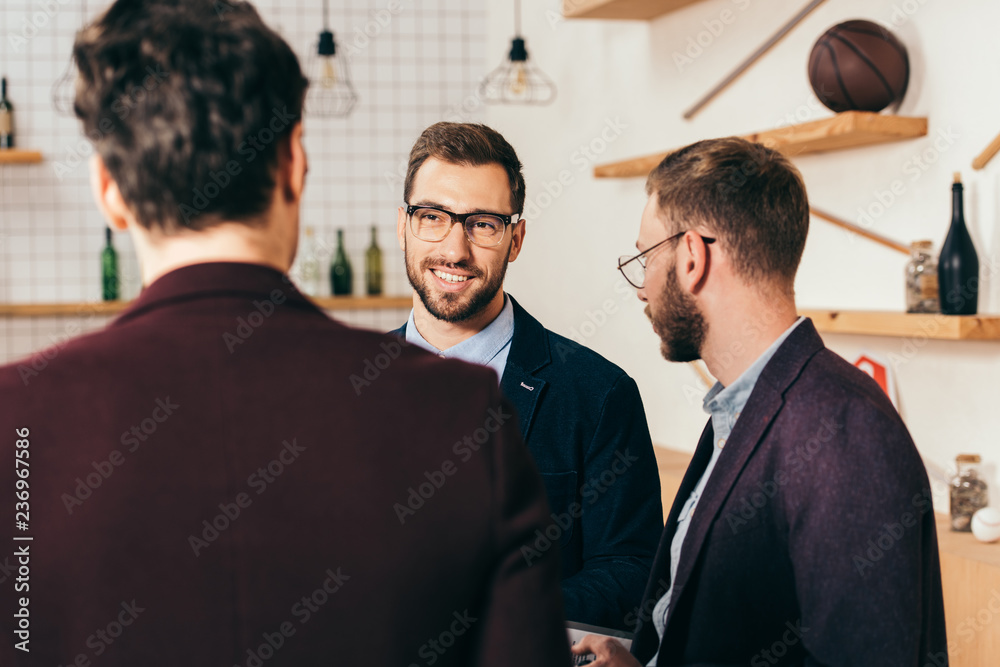 selective focus of smiling businessman looking at colleague in cafe selective focus of smiling businessman looking at colleague in cafe