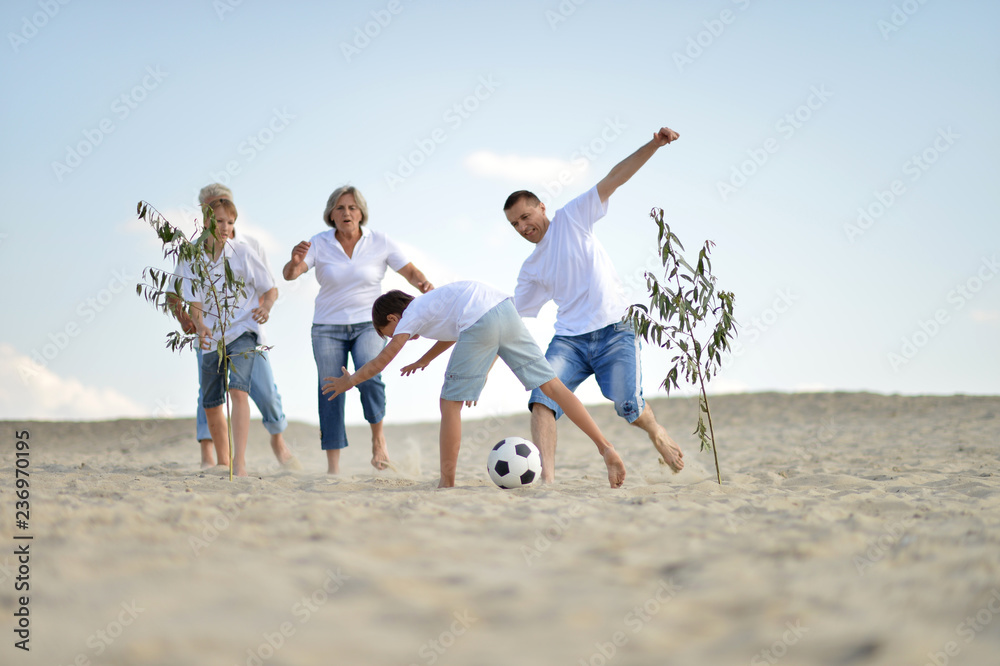 Happy family playing football on a beach in summer day Happy family playing football on a beach in summer day